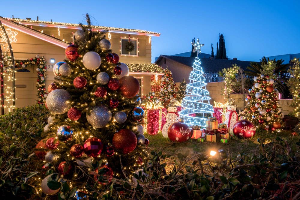 Full residential lawn display with decorated trees, gifts, and holiday sculptures