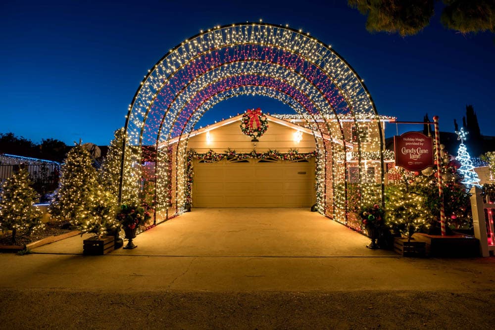 Home entrance framed with illuminated arches, trees, wreaths, and garland