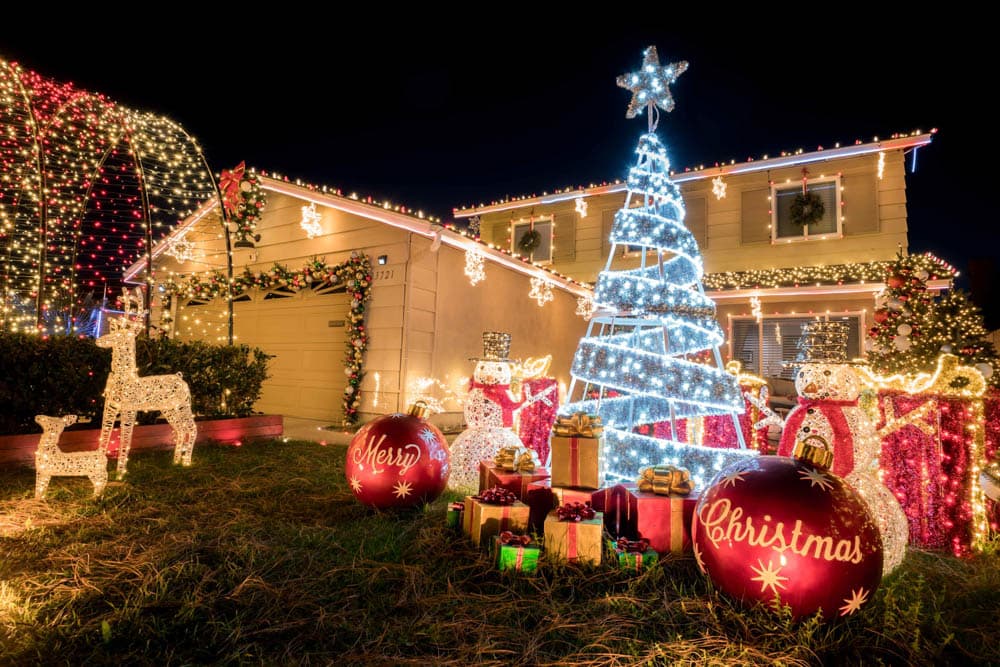 Two-story home with colorful roofline lights and an illuminated Christmas display