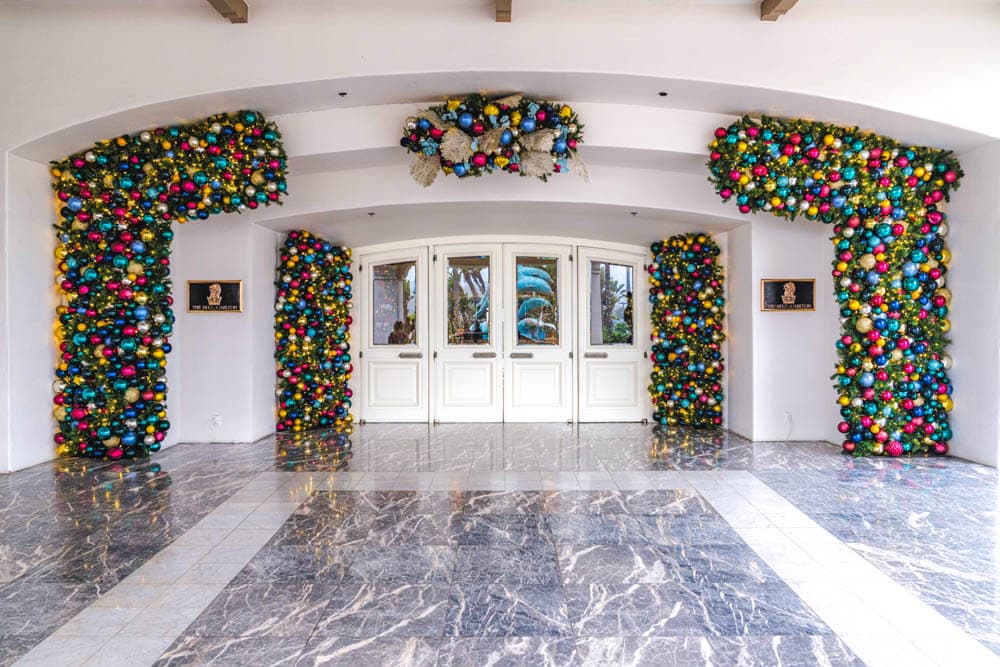 Luxury hotel entrance framed by dense multicolor ornaments and holiday greenery