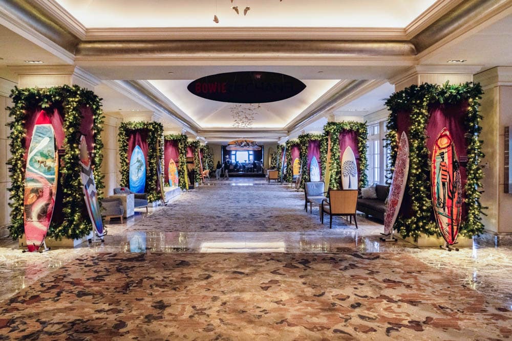 Surfboard displays framed by illuminated holiday greenery inside a hotel