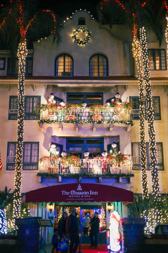 Mission Inn facade, balconies, and palm trees covered in coordinated holiday lighting
