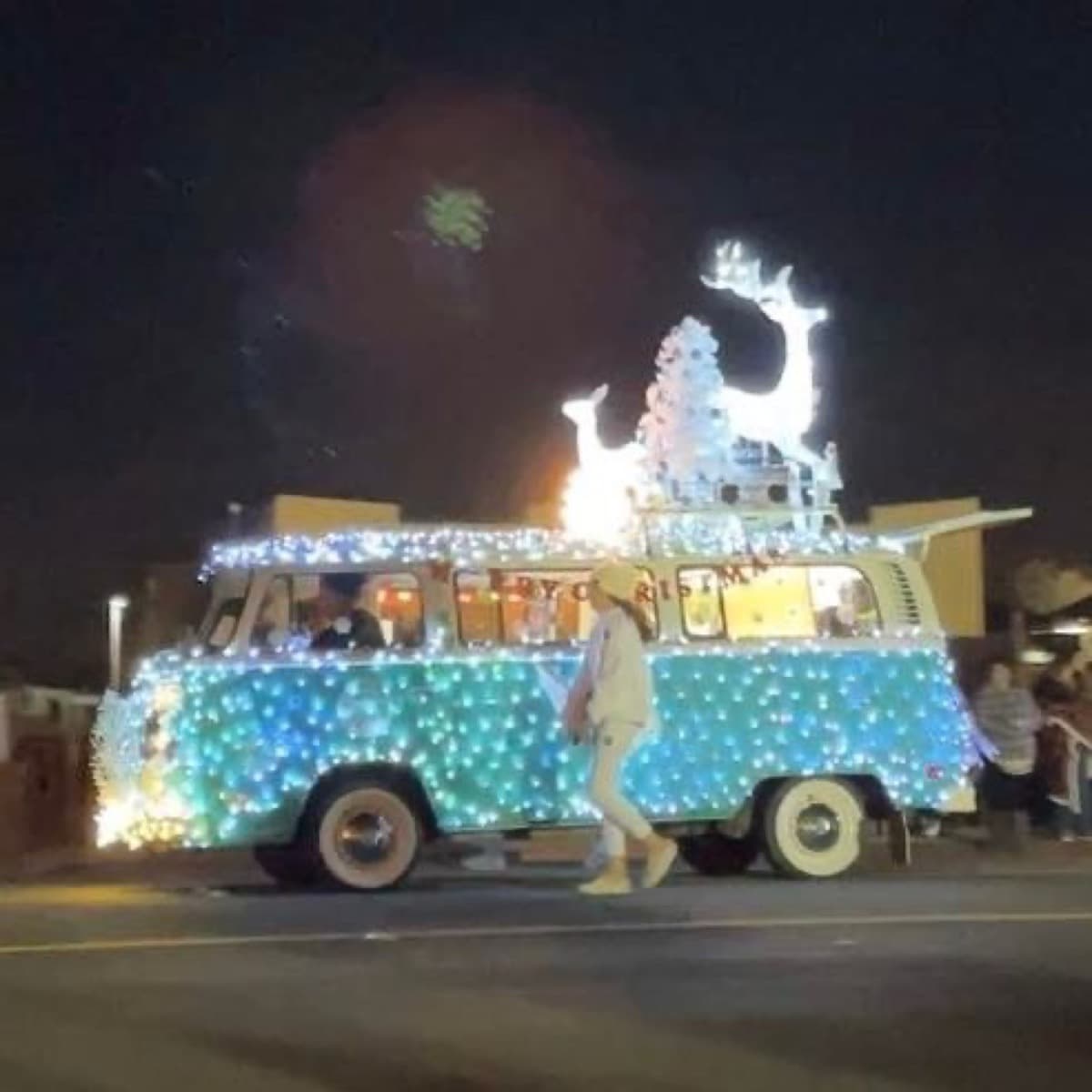 A vintage blue van covered in white and blue lights during Beaumont's holiday parade