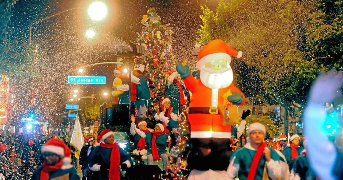 A Santa float and costumed marchers surrounded by falling snow on Second Street