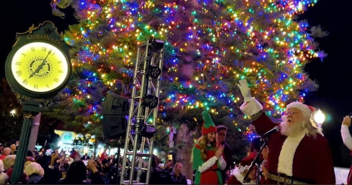 Santa waving beside Coronado's brightly illuminated community Christmas tree