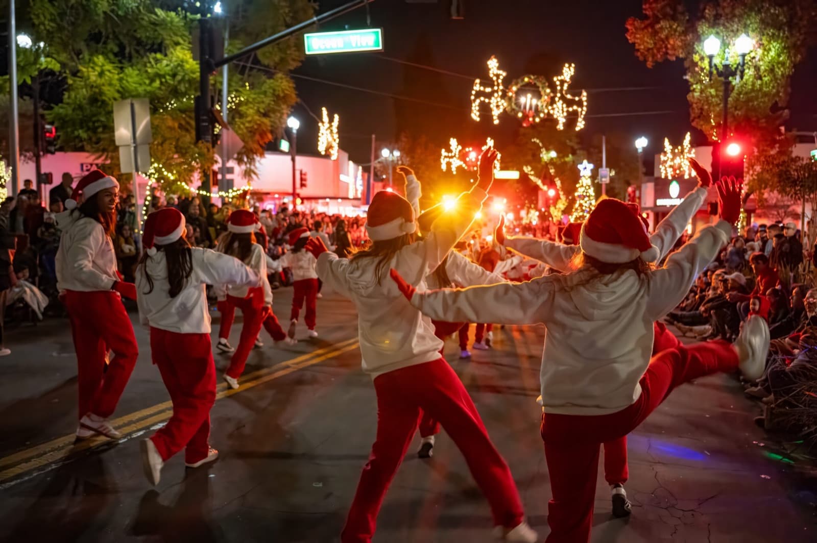 Dancers in Santa hats performing on holiday-lit Honolulu Avenue at night