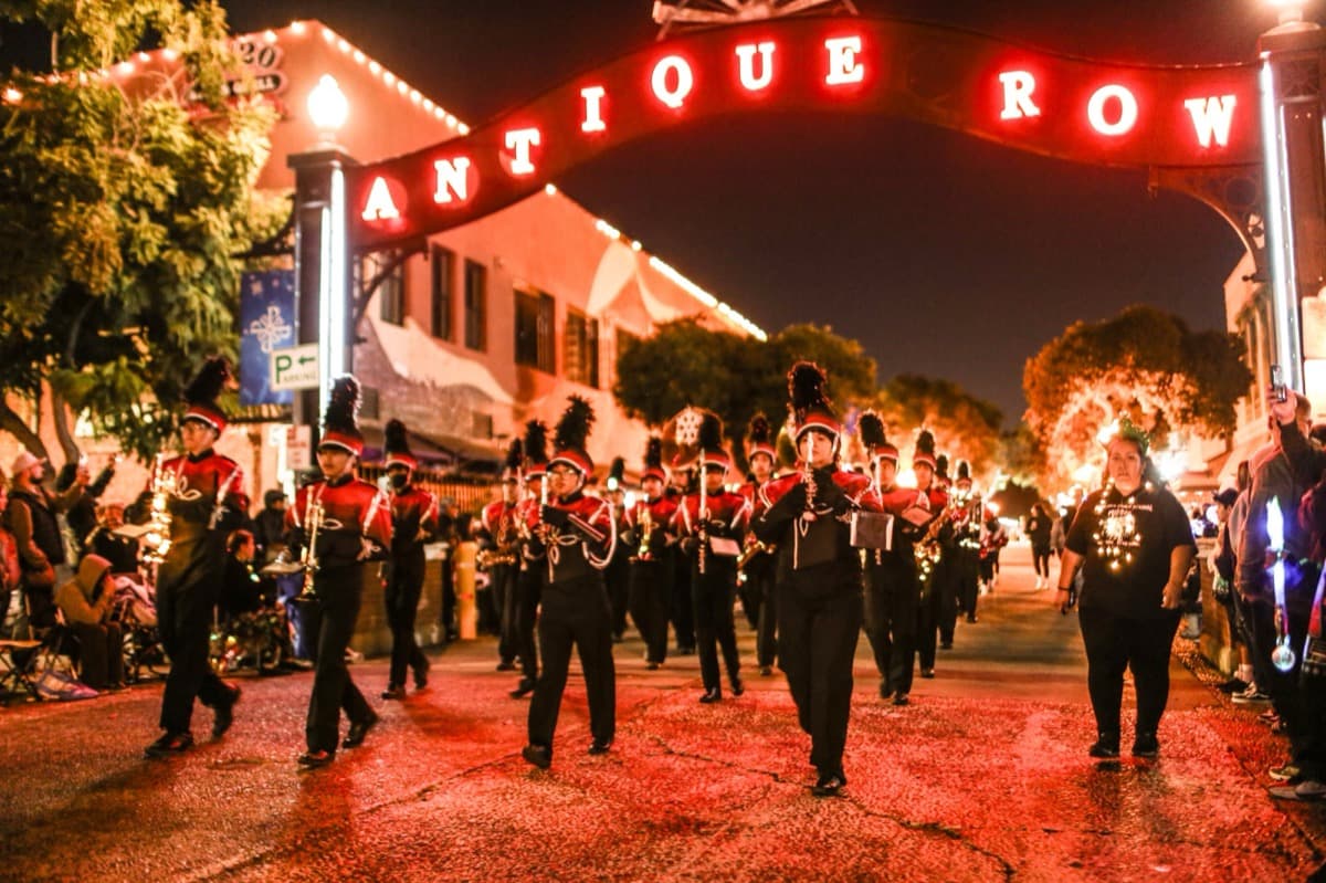 A marching band performing beneath the Antique Row arch during Pomona's holiday parade