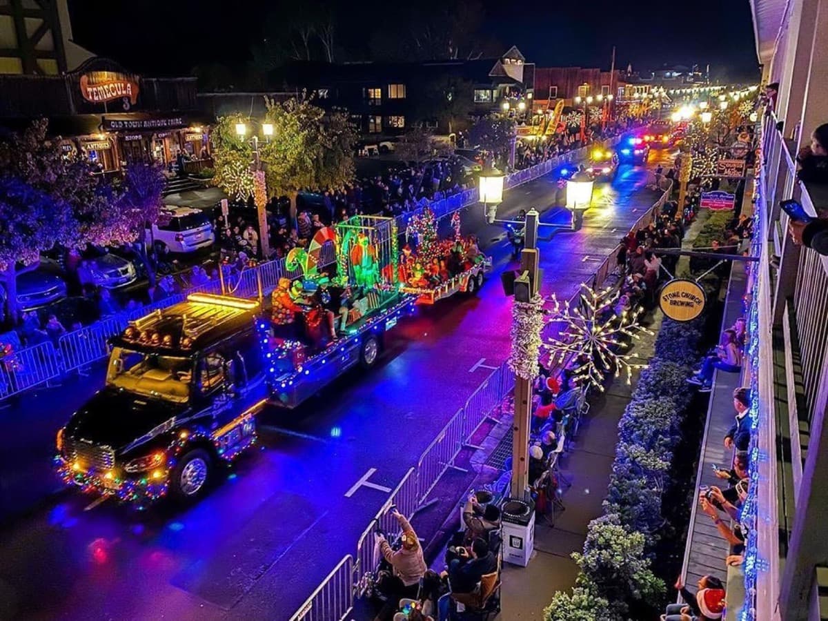 An illuminated Christmas float traveling through Old Town Temecula at night