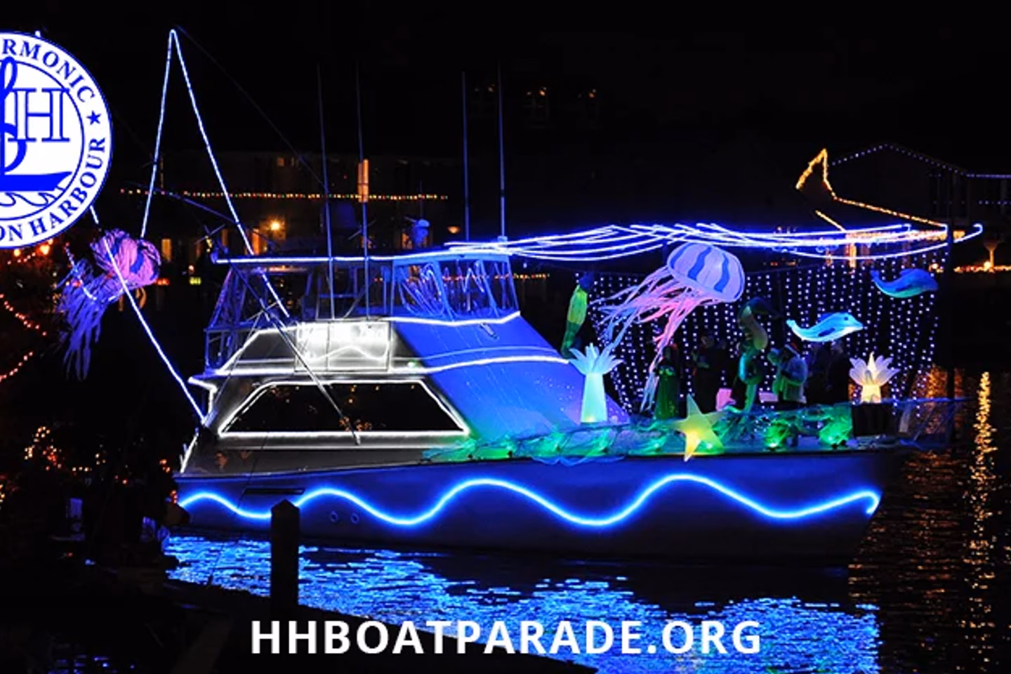 A boat covered in blue and white holiday lights during the Huntington Harbour Boat Parade