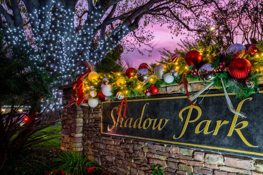 Shadow Park monument and mature tree decorated with garland, ornaments, and holiday lights by HLI in Cerritos
